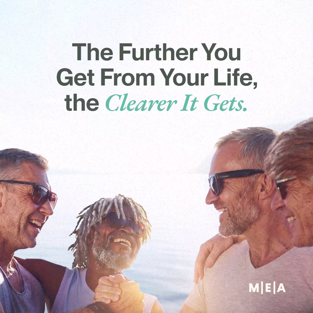 Four men laughing together on a sunny beach